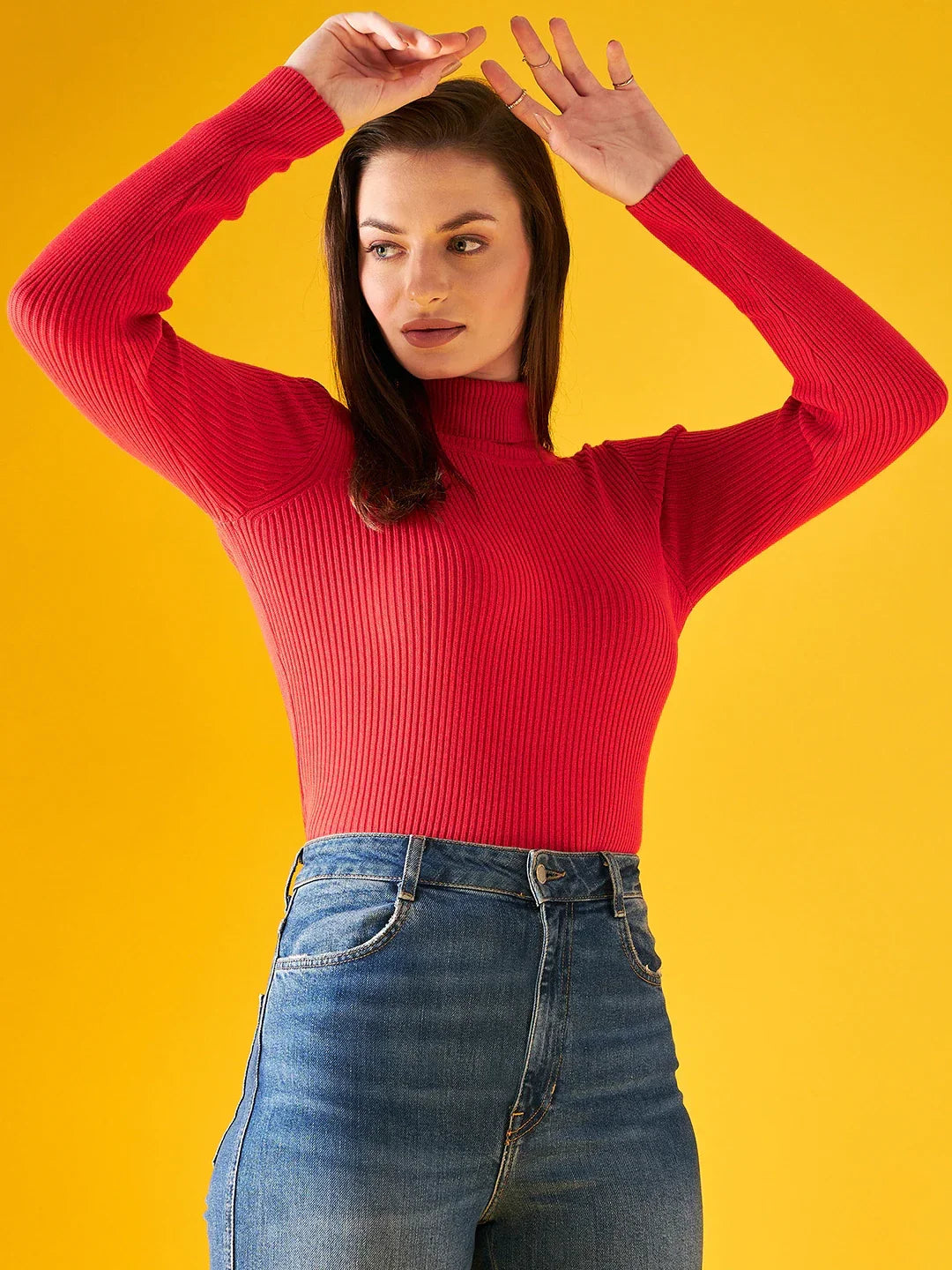 Woman poses with arms raised in 98degreenorth’s bright red ribbed turtleneck sweater for Indian winters.