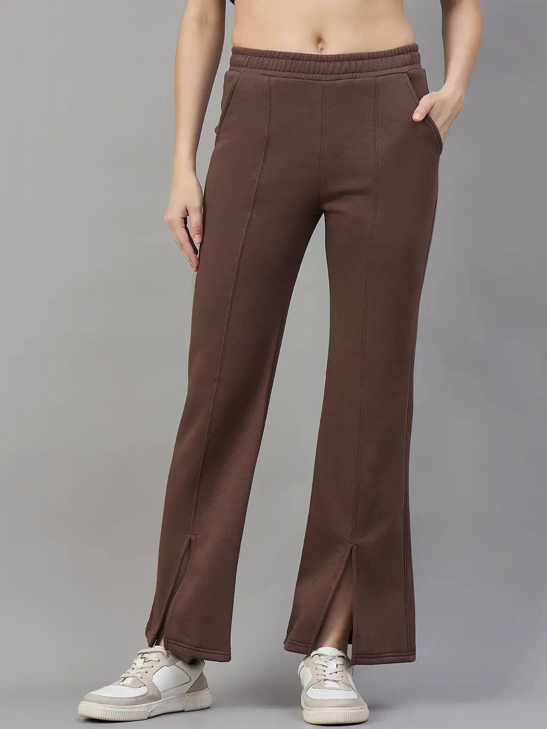 Model wears 98degreenorth Cocoa Brown Women’s Fleece Flared Sweatpants with front slits, white sneakers, and a crop top.