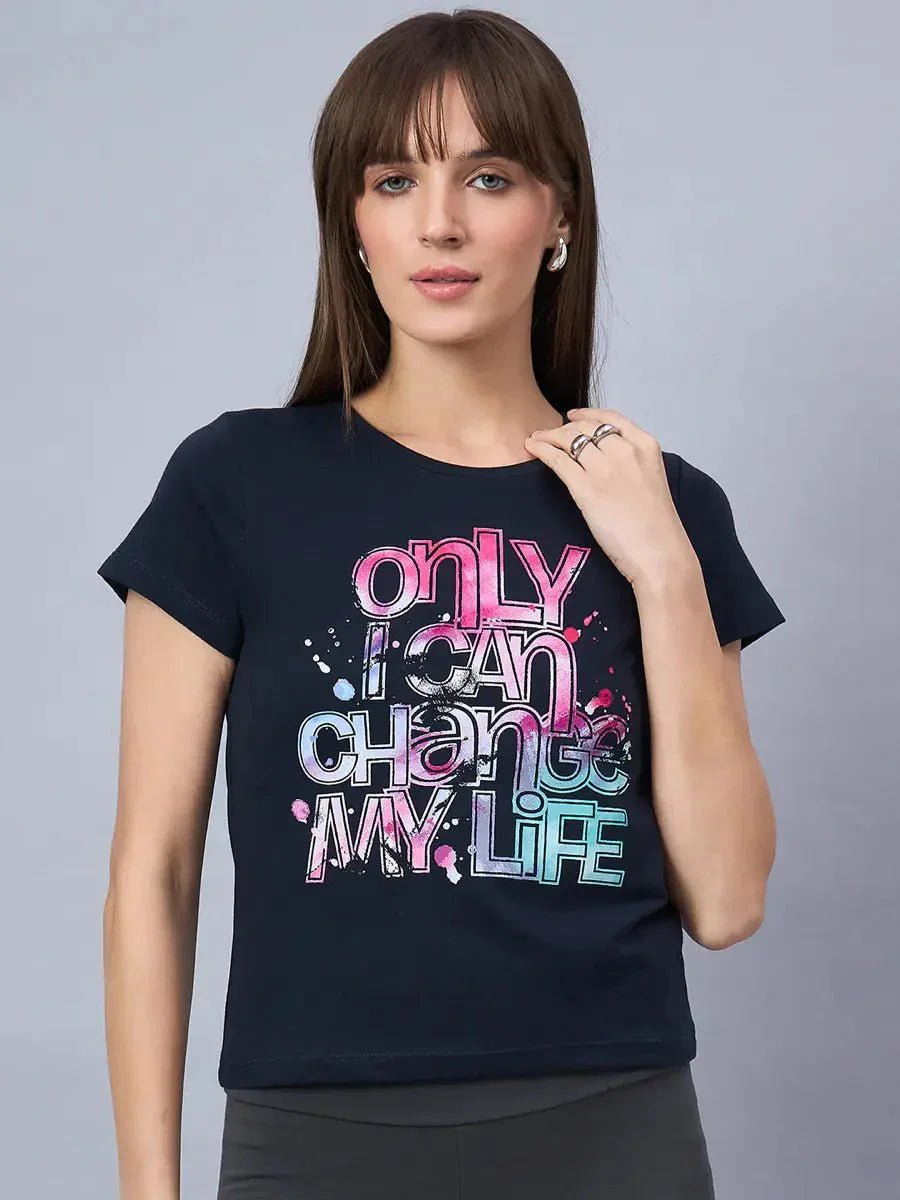 Woman wears 98degreenorth soft cotton typography t-shirt—an essential for daily wear—on a plain background.