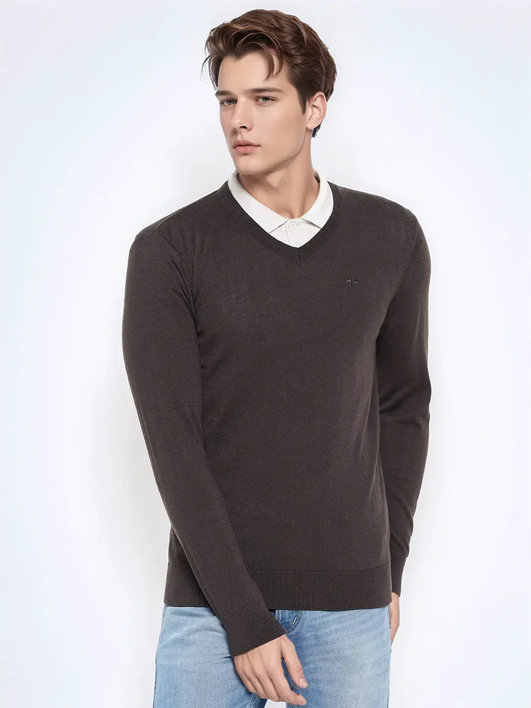 Man wears 98degreenorth Men’s Anthra Merino Wool V-Neck Sweater over a white shirt and light blue jeans.