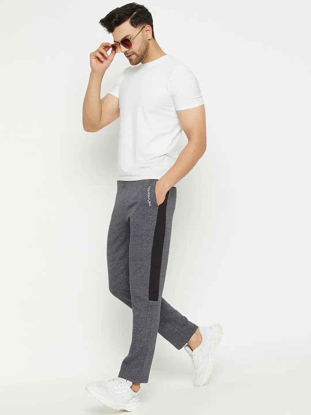 Man in sunglasses, white tee, and 98degreenorth Black Jaspe Fleece Trackpants, walking in white sneakers.