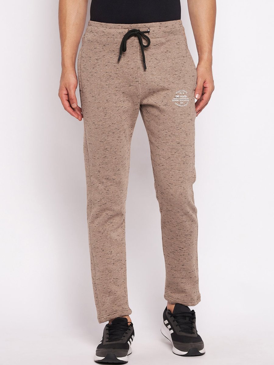 Man wears 98degreenorth Men’s Camel Melange Fleece Trackpants with black drawstring and sneakers, on white backdrop.
