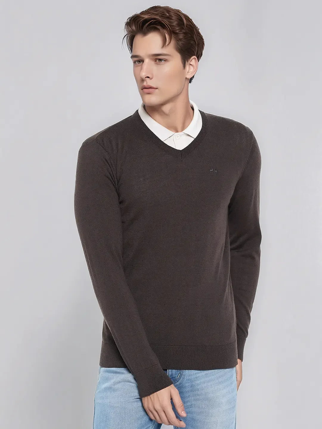 Man wears 98degreenorth Men’s Charcoal Merino Wool V-Neck Sweater over a white shirt and jeans, against a plain backdrop.