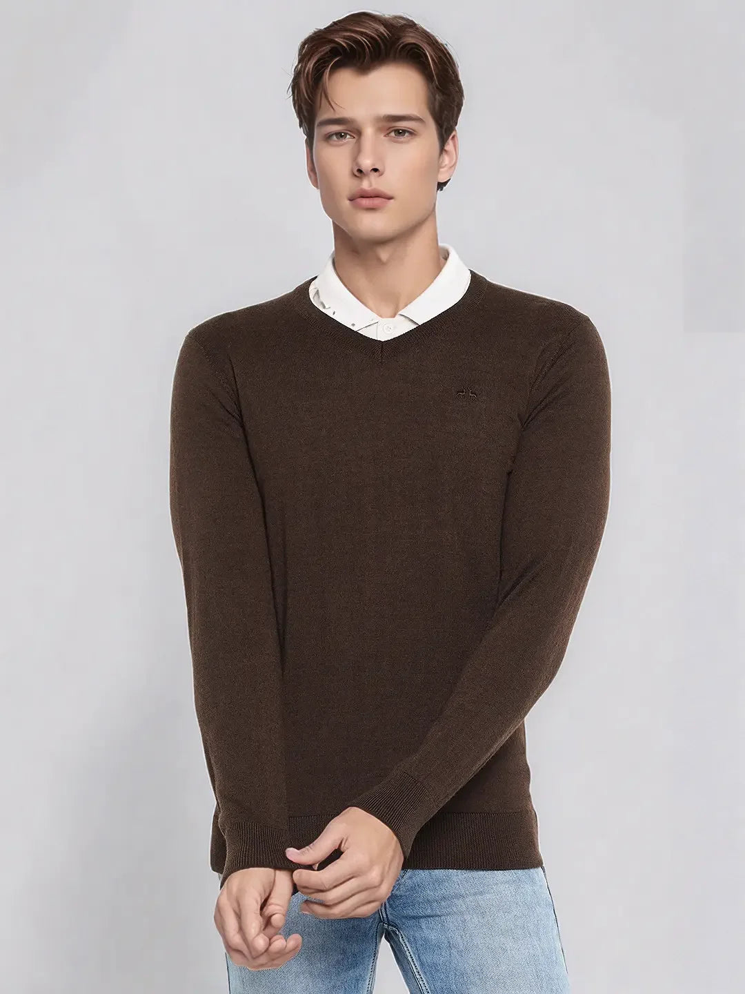 A man wears the 98degreenorth Men’s Coffee Merino Wool V-Neck Sweater against a plain background.