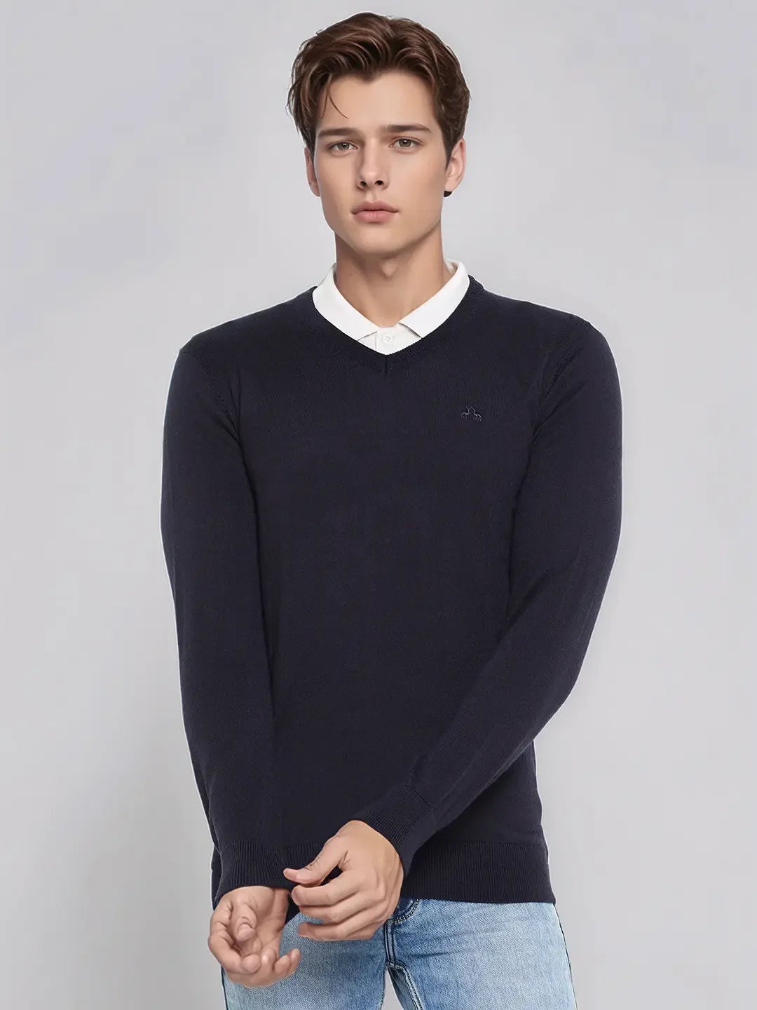 A man wears the 98degreenorth Men’s Dark Navy Merino Wool V-Neck Sweater, standing against a light gray background.