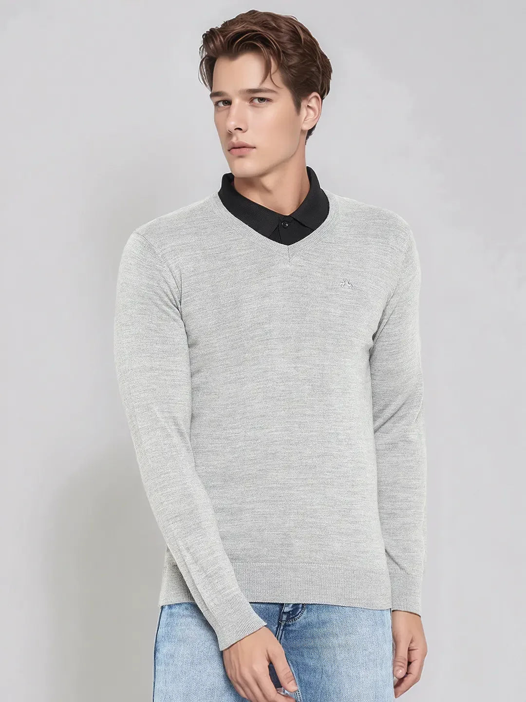 Young man in a 98degreenorth light grey Merino wool V-neck sweater for work, over a black shirt and jeans.