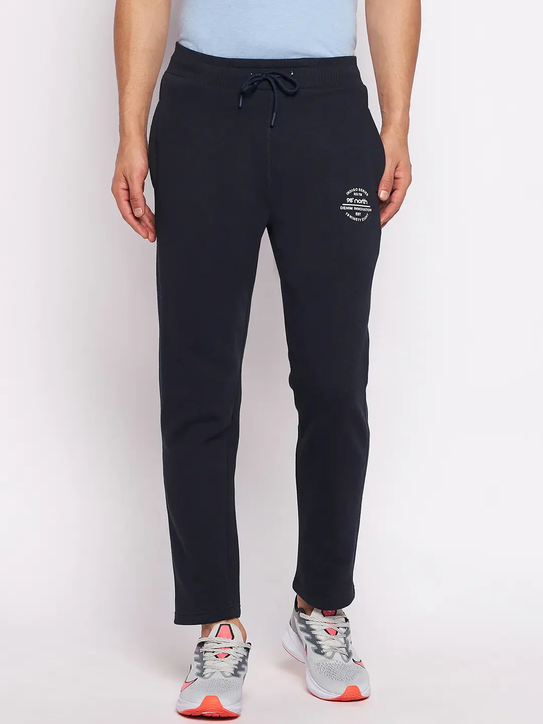 Wearing 98degreenorth Men’s Navy Fleece Trackpants, paired with gray sneakers with orange accents.
