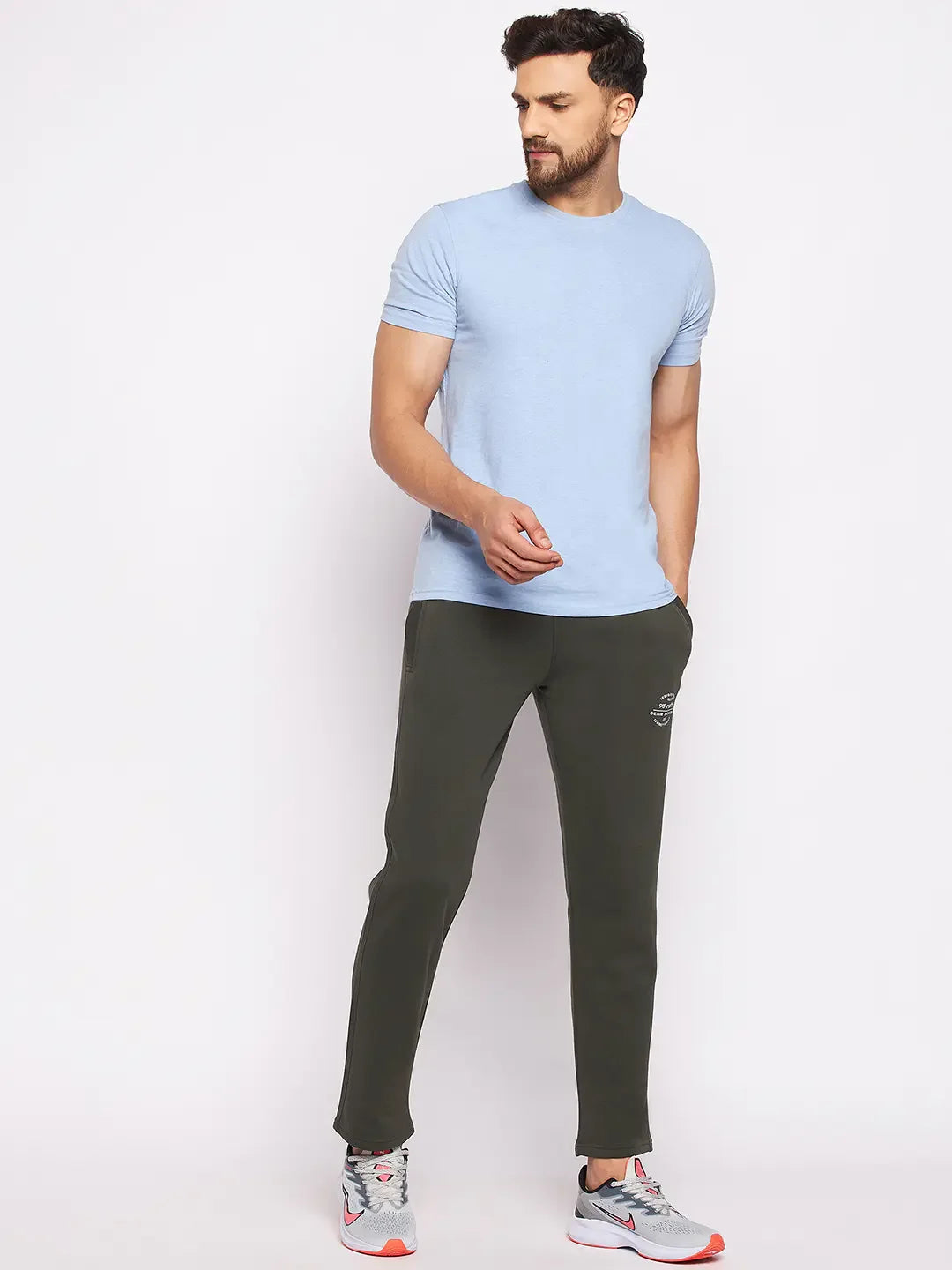 Man in 98degreenorth Olive Fleece Trackpants and gray sneakers, standing against a plain white background.