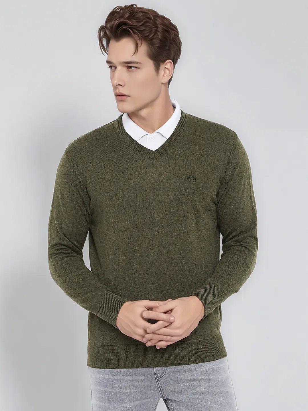 Young man in a 98degreenorth olive merino wool V-neck sweater, white collared shirt, and light gray pants.