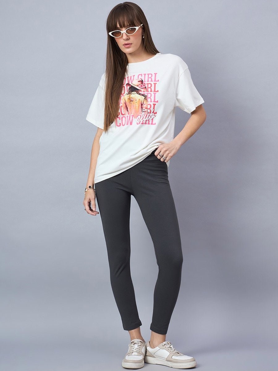 Woman in 98degreenorth Offwhite Typography Graphic Cotton Tee—drop shoulder streetwear—plus black leggings and sneakers.