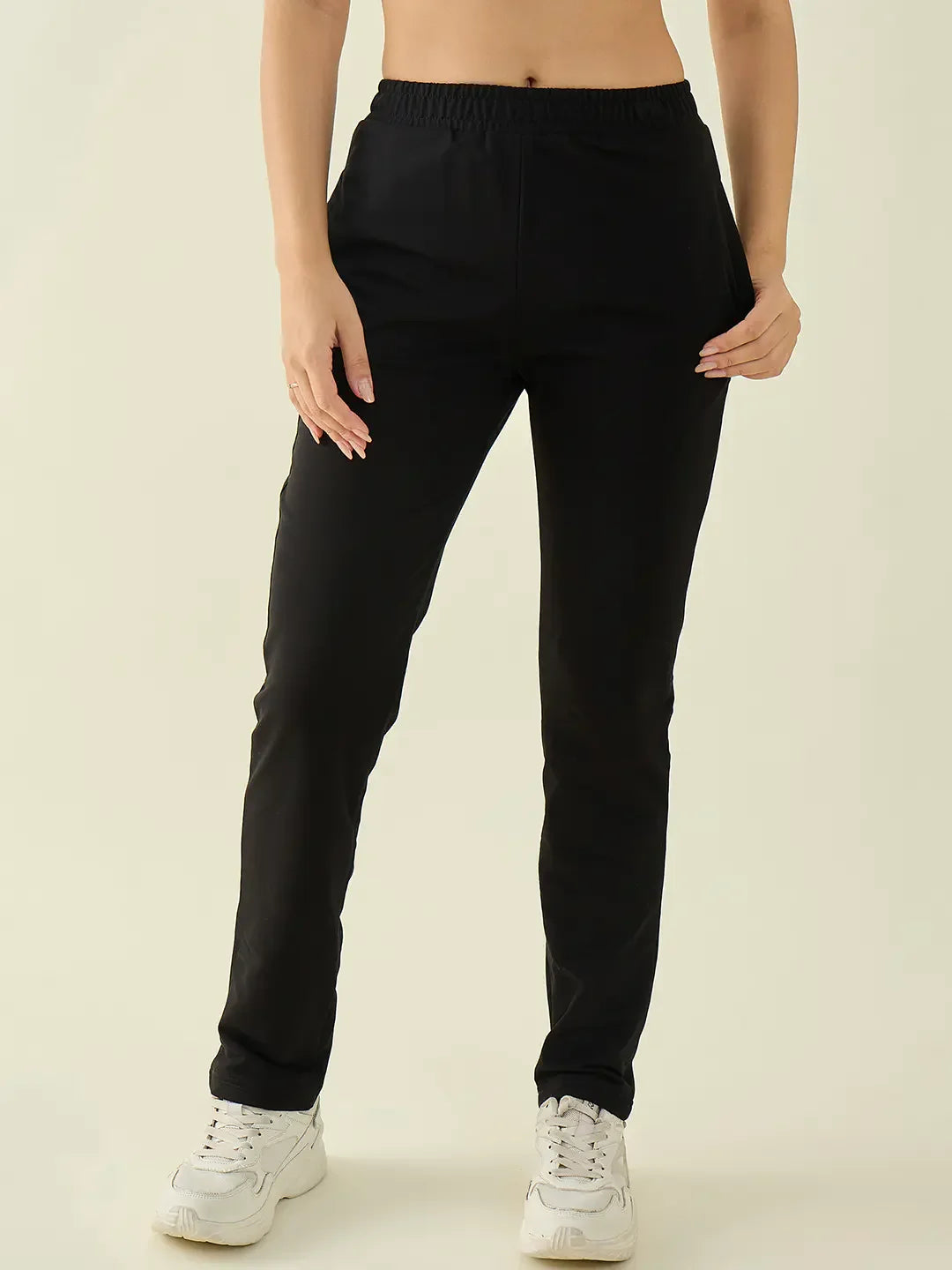 Model wears 98degreenorth Women’s Black Regular Fit Stretchable Trousers, styled with white sneakers.