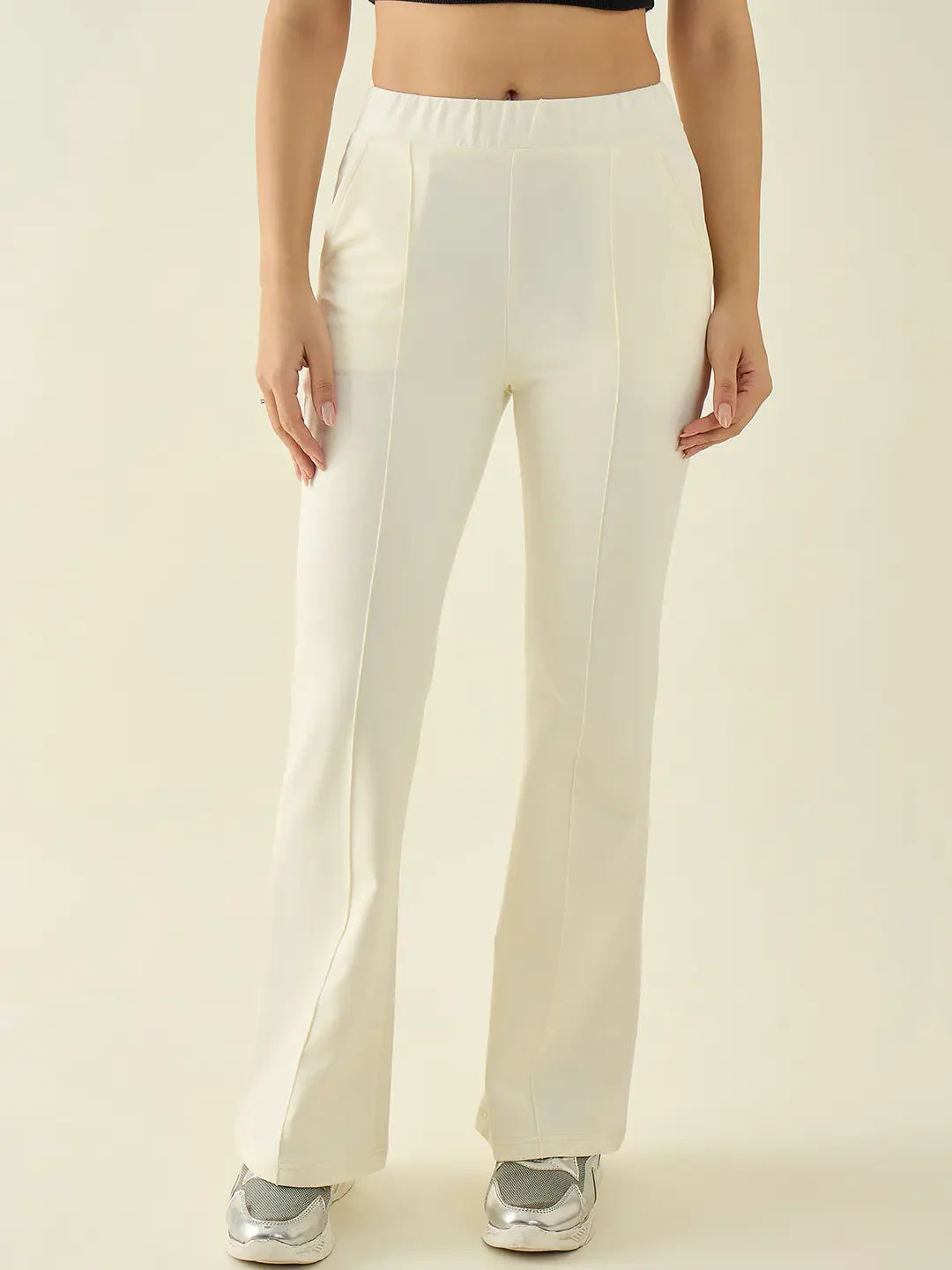 Woman wears 98degreenorth Women’s Butter Flared Bootcut Cotton Stretchable Trousers with sneakers, neutral background.
