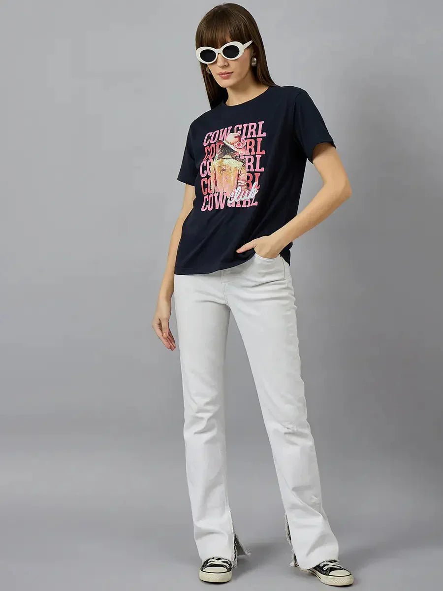 Woman in white sunglasses, 98degreenorth cotton typography graphic tee, white pants, and black-and-white sneakers.