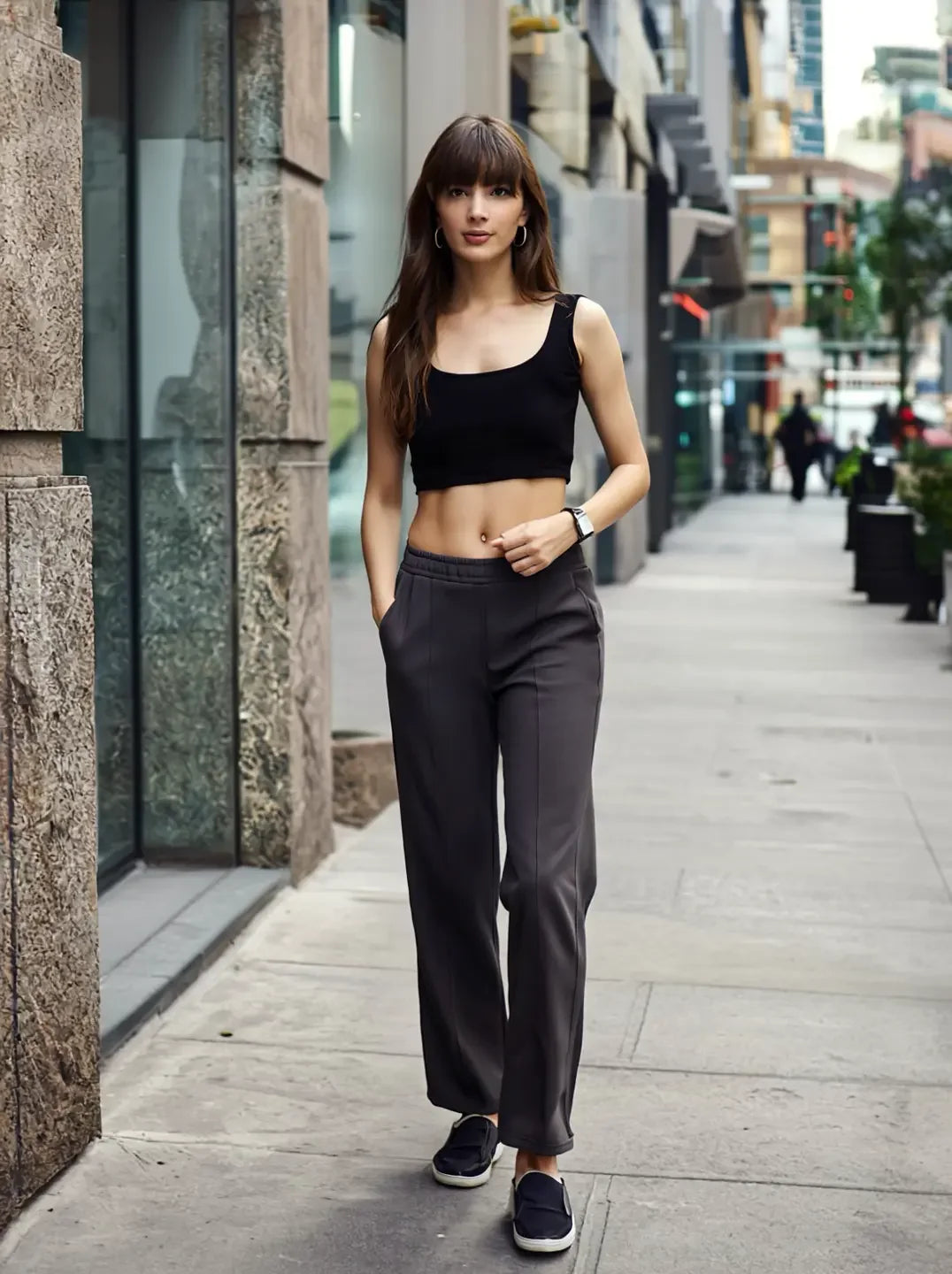 A woman in a black crop top and 98degreenorth’s Charcoal Grey Flared Sweatpants walks confidently down a city street.
