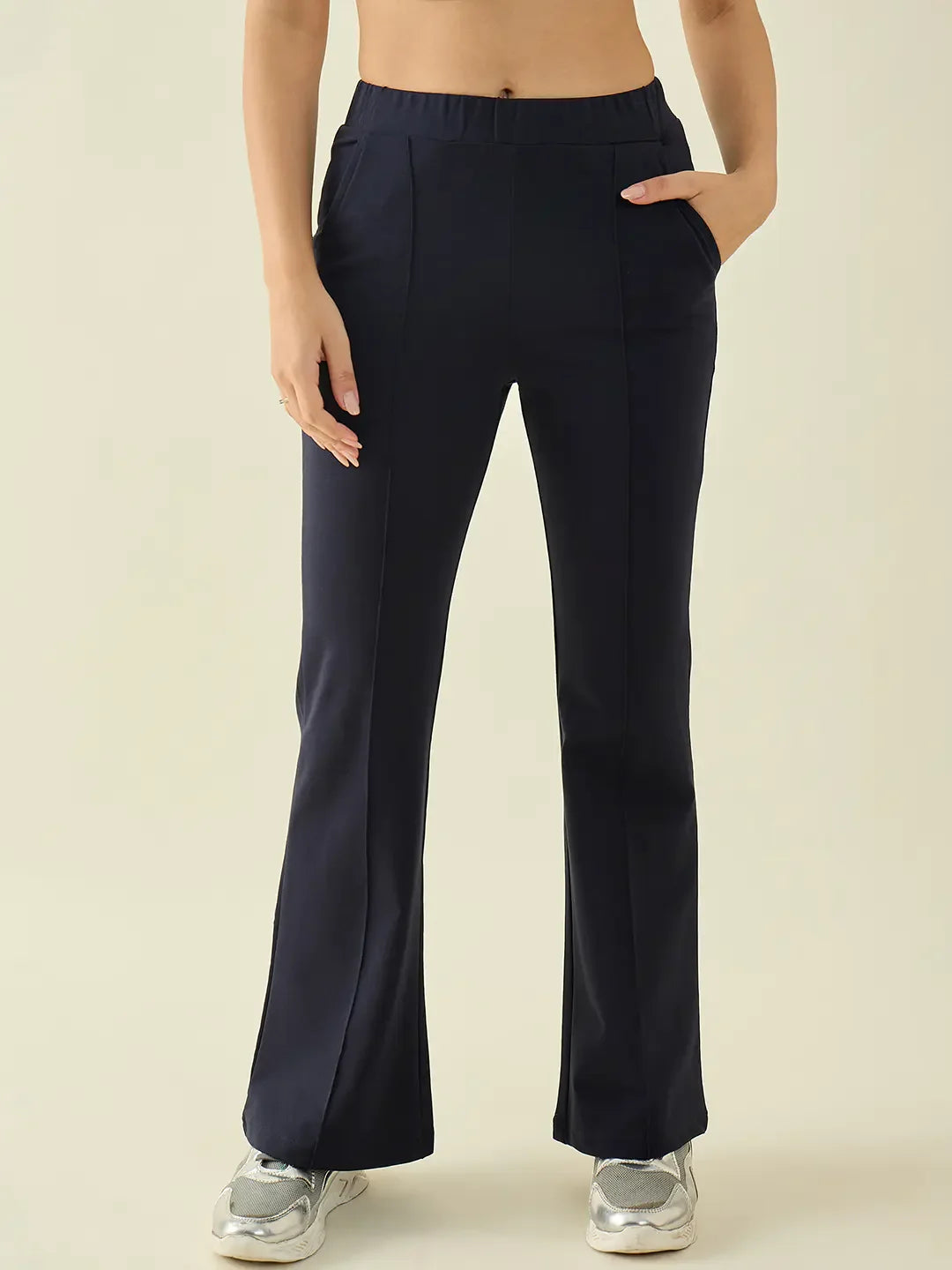 Woman wears 98degreenorth Navy Flared Bootcut Cotton Stretchable Trousers, hands in pockets, on plain background.