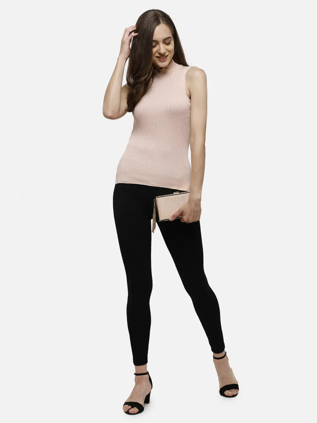 Woman wears 98degreenorth Women’s Pink Ribbed High Neck Sleeveless Knit Top, black leggings, heels, and a beige clutch.