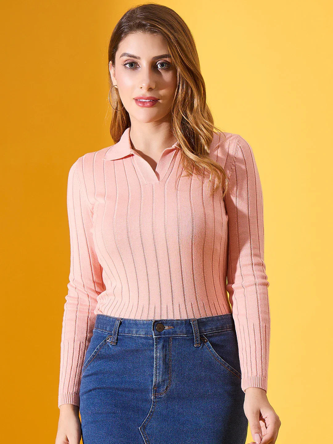 Woman wears a 98degreenorth salmon ribbed collar neck sweater and blue denim skirt against a yellow background.