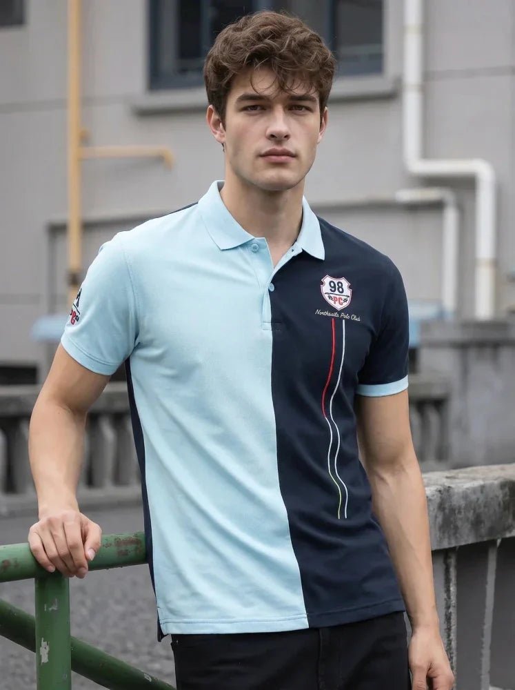 Man wearing a mustard brown short-sleeve polo shirt and light blue jeans, standing against a plain white background, looking to his left with one hand by his side.