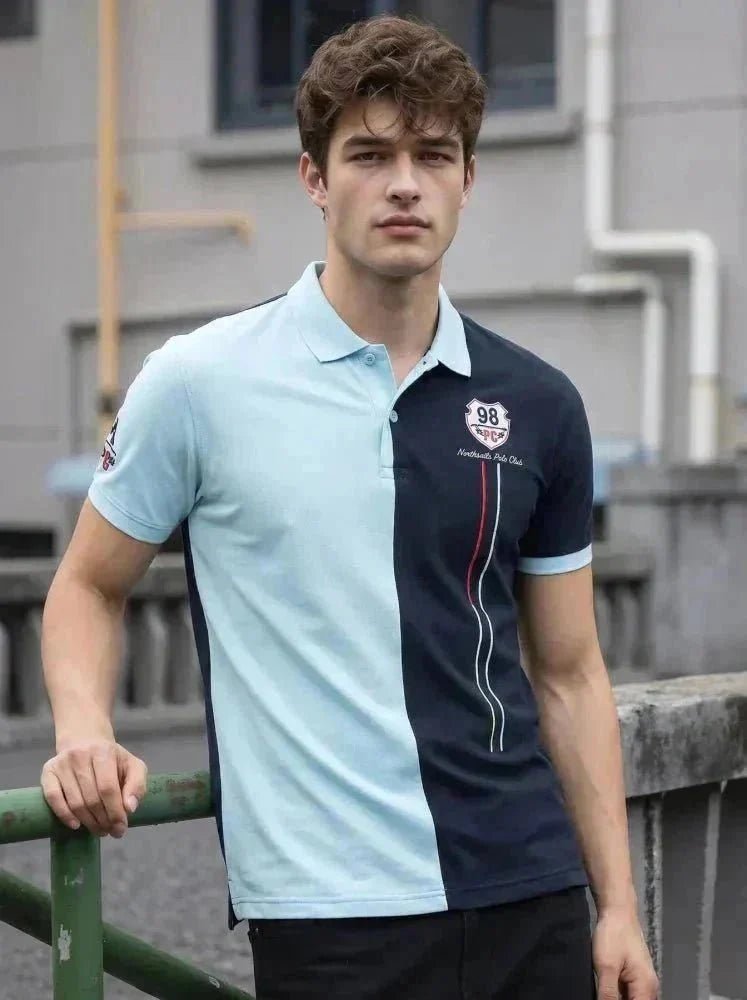 Man wearing a mustard brown short-sleeve polo shirt and light blue jeans, standing against a plain white background, looking to his left with one hand by his side.