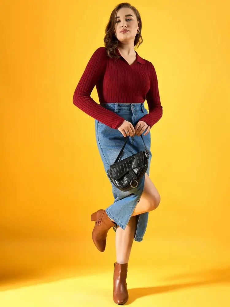 A woman poses against a yellow background, wearing a red long-sleeve top, blue buttoned denim skirt, brown ankle boots, and holding a black handbag.