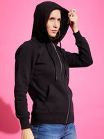 Woman wears 98degreenorth black fleece zipper hoodie with blue jeans, standing against a bright pink background.