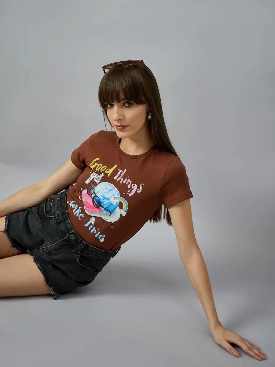 Woman wears 98degreenorth’s breathable cotton typography tee, styled streetwear, with black shorts against a gray backdrop.