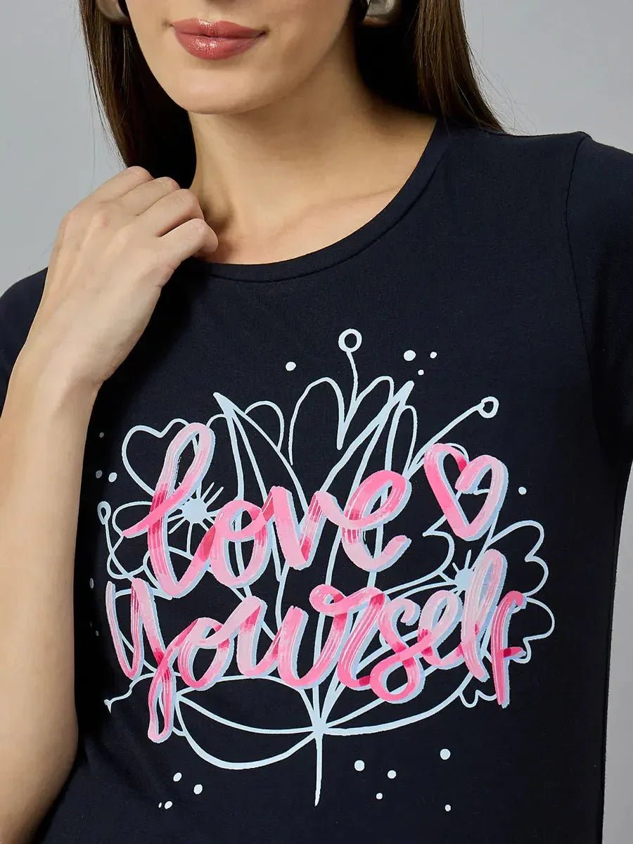 A woman wears a 98degreenorth navy cotton typography tee with love yourself and a heart in pink and white on the front.