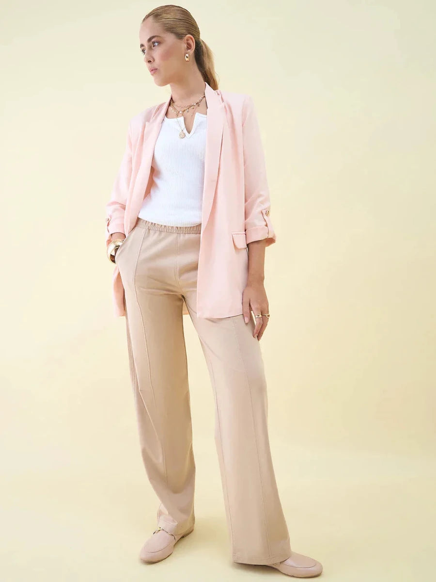 Woman in light pink blazer, white top, and 98degreenorth Beige Wide Leg Pintuck Trackpants, standing against a pale background.