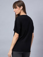 Woman with long brown hair wears a 98degreenorth Black Typography Printed Oversized Cotton T-shirt, facing away.