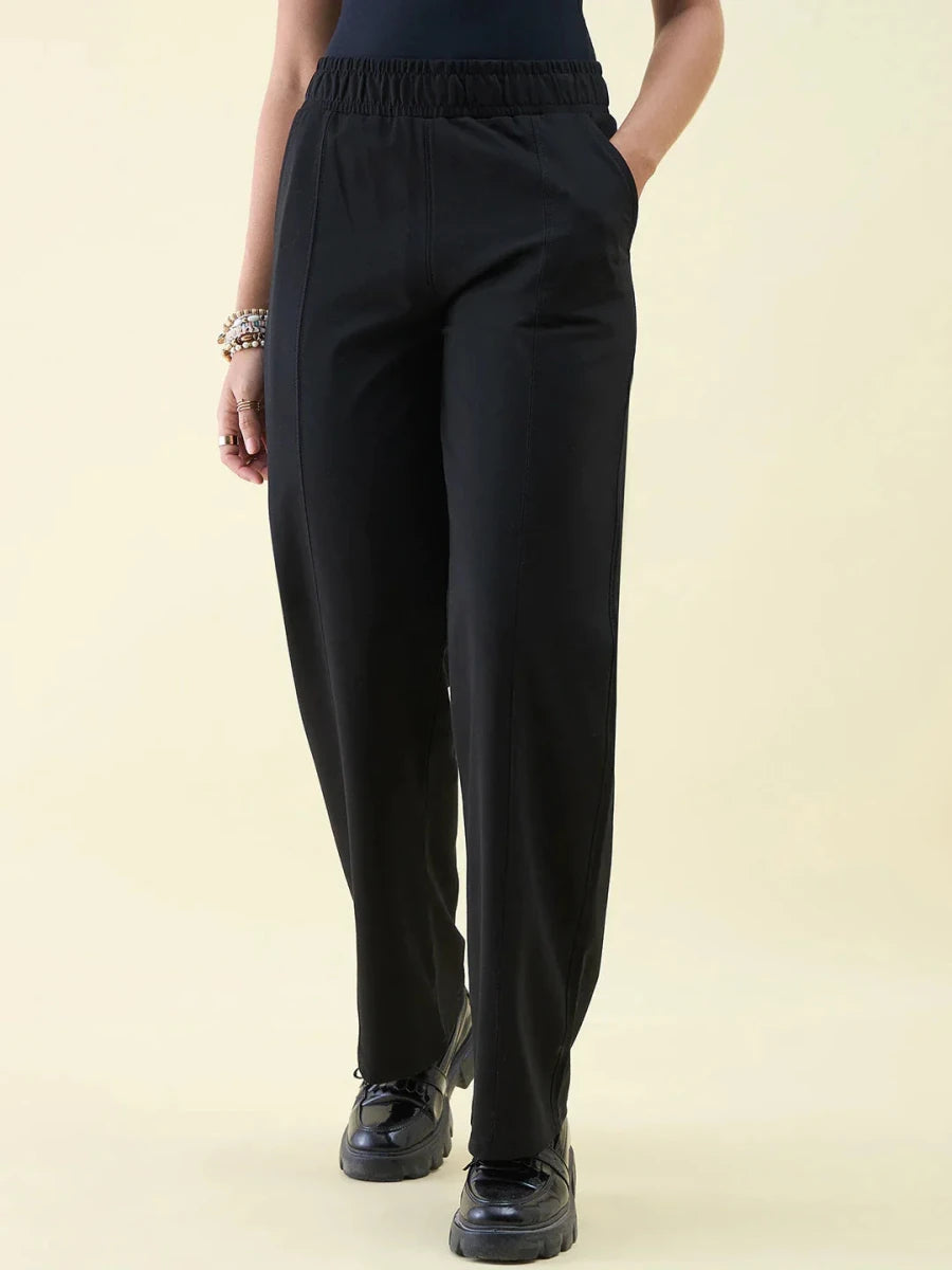 Wearing 98degreenorth Black Wide Leg Pintuck Trackpants, black shoes, and bracelets; hands in pockets.