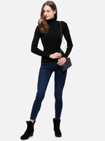 Woman in 98degreenorth Black Ribbed Stretchable Turtleneck Sweater, dark blue jeans, boots & a black crossbody purse.
