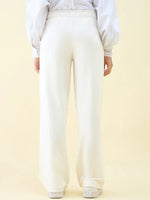 Person wears 98degreenorth Butter Wide Leg Pintuck Trackpants and a white blouse, shown from the back on a light backdrop.