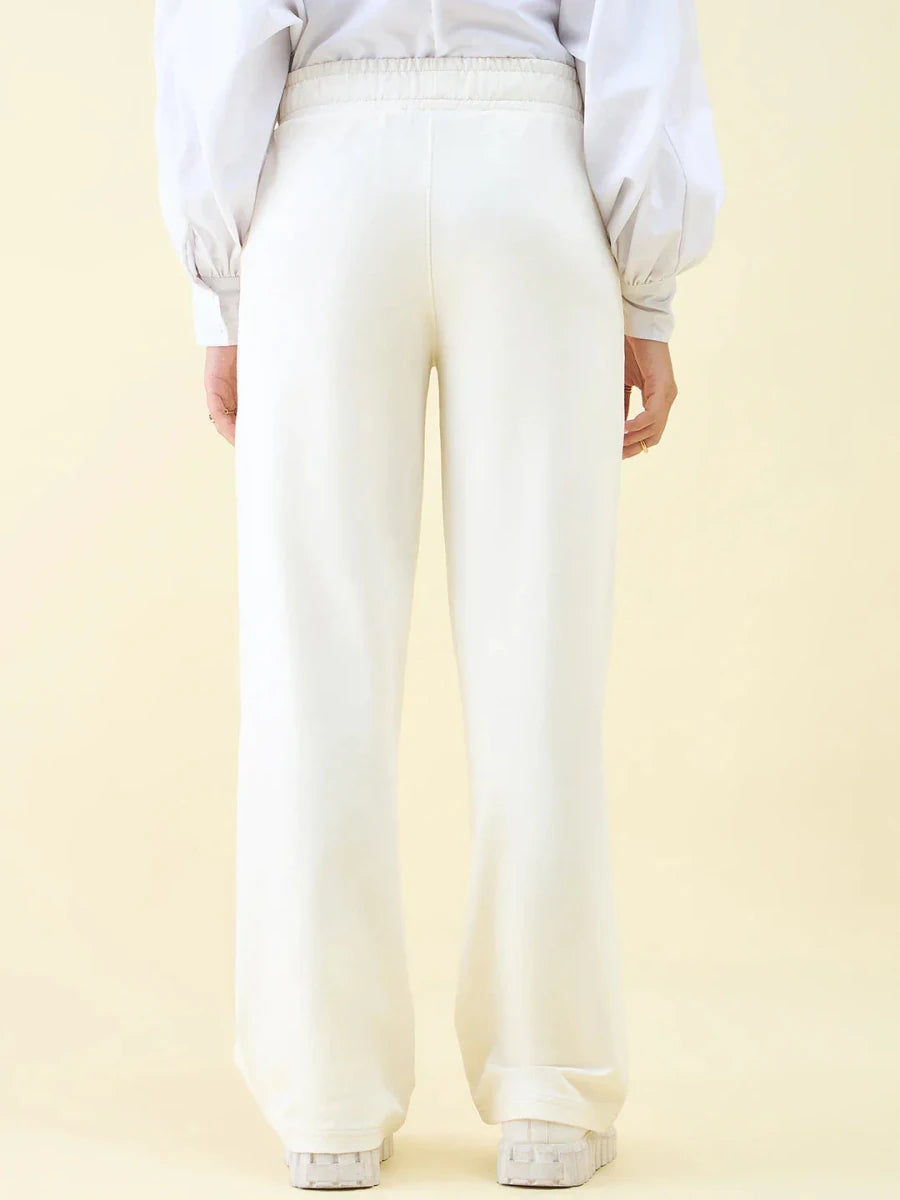 Person wears 98degreenorth Butter Wide Leg Pintuck Trackpants and a white blouse, shown from the back on a light backdrop.