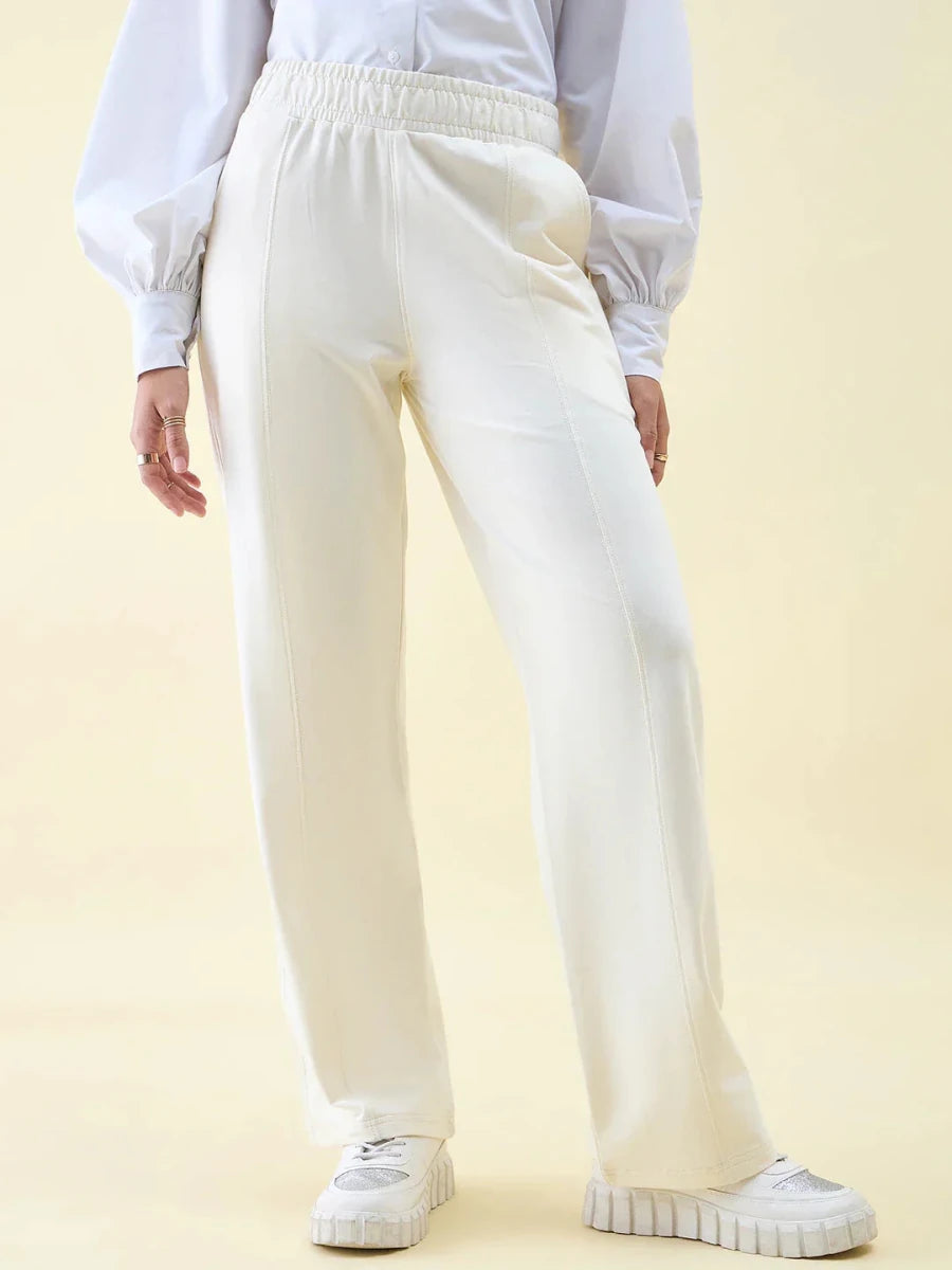 Person in 98degreenorth Butter Wide Leg Pintuck Trackpants, white sneakers, and a white puffy long-sleeve shirt.