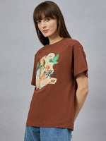 Woman in 98degreenorth Casual Typography Print Cotton T-shirt, drop shoulder style, and blue jeans against a gray wall.