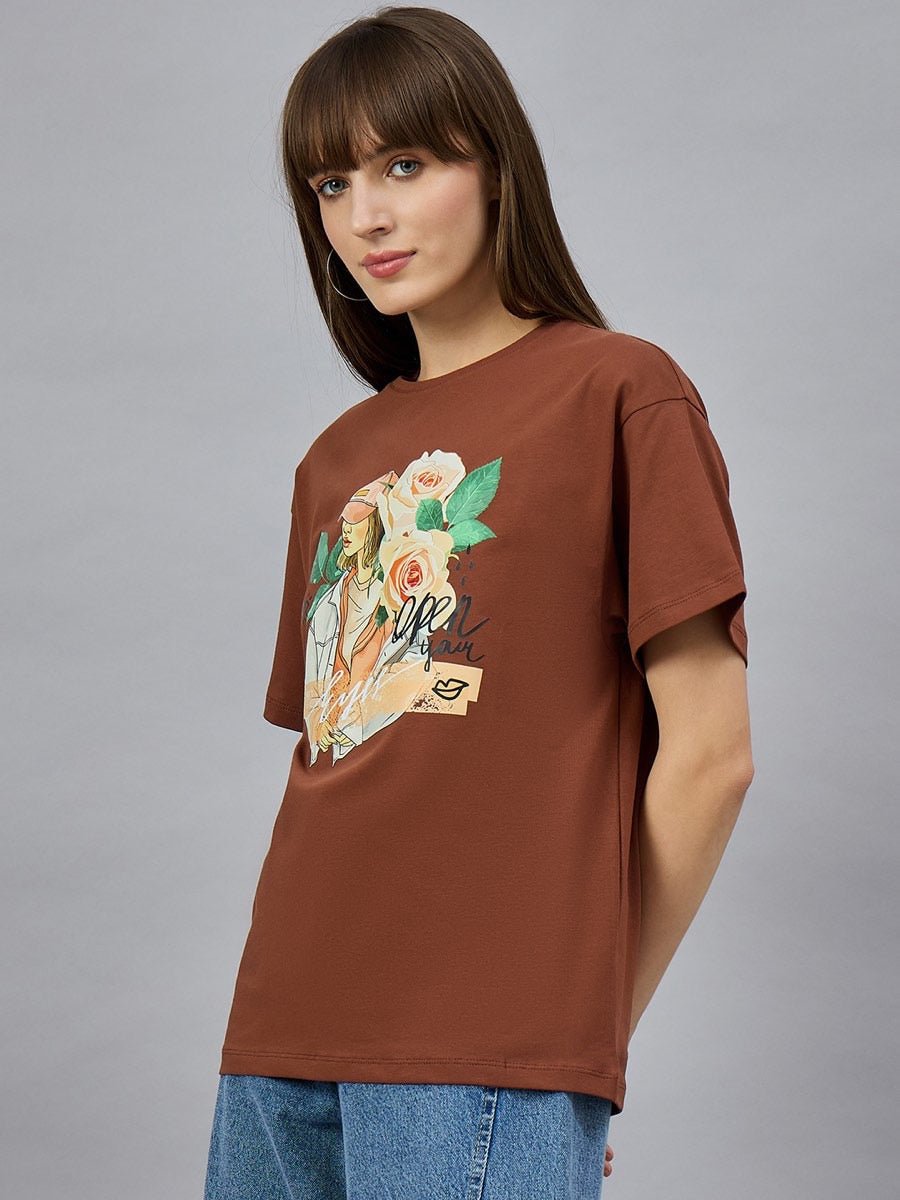 Woman in 98degreenorth Casual Typography Print Cotton T-shirt, drop shoulder style, and blue jeans against a gray wall.