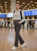 A woman in 98degreenorth Charcoal Grey Fleece Flared Sweatpants walks in an airport with a backpack and white sneakers.