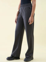 Person wears 98degreenorth Charcoal Wide Leg Pintuck Trackpants, styled Luxe Lounge, with black shoes on a light background.
