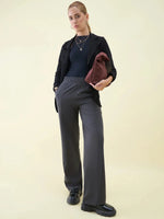 Woman in black top, blazer, and 98degreenorth Charcoal Wide Leg Pintuck Trackpants holding a brown bag.