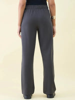 Person in 98degreenorth Charcoal Wide Leg Pintuck Trackpants and black top, shown from the back, gold bracelet on left wrist.