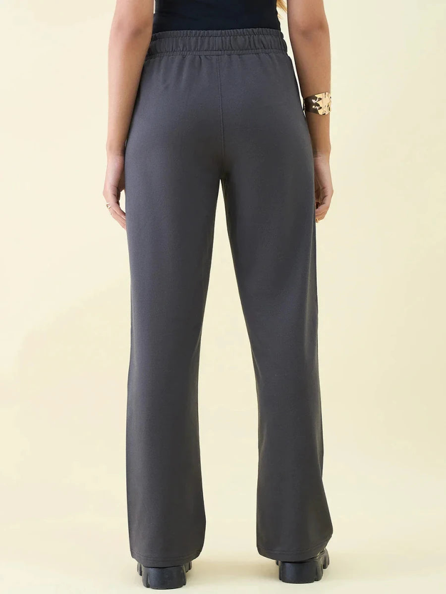 Person in 98degreenorth Charcoal Wide Leg Pintuck Trackpants and black top, shown from the back, gold bracelet on left wrist.
