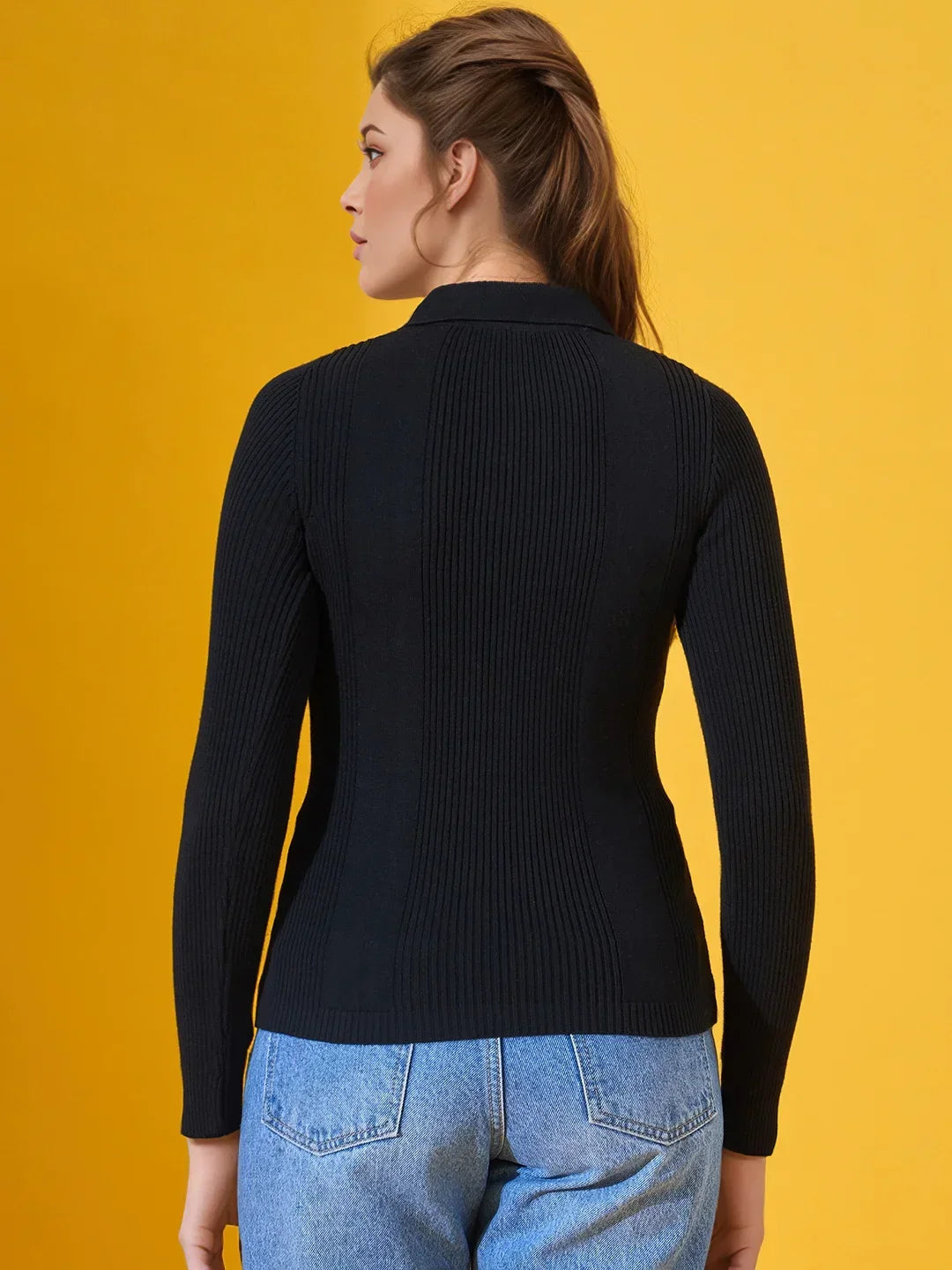 Woman wears 98degreenorth’s Classic Black Women’s Ribbed Polo-Neck Knit Top, facing away against a yellow background.