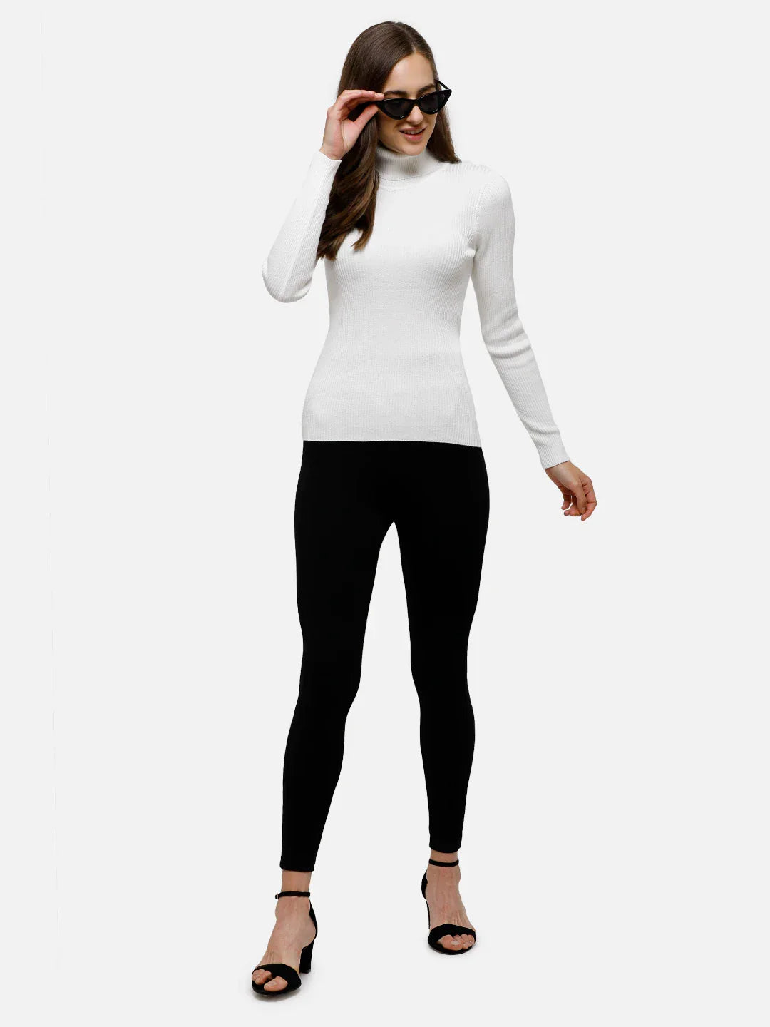Woman wears 98degreenorth Classic White Ribbed Turtle Neck Sweater, black sunglasses, leggings, and heels, smiling.