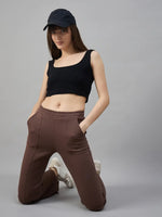 Woman in a black crop top and 98degreenorth Cocoa Brown Fleece Flared Sweatpants kneels by a gray background.