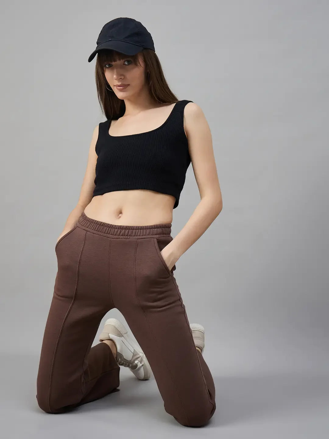 Woman in a black crop top and 98degreenorth Cocoa Brown Fleece Flared Sweatpants kneels by a gray background.