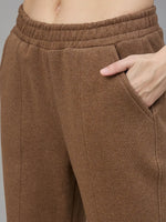 A person models 98degreenorth Coffee Melange Women’s Fleece Bootcut Sweatpants, one hand in pocket, waist down view.