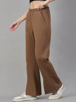 Model in 98degreenorth Coffee Melange Women’s Fleece Bootcut Sweatpants and white sneakers, against a grey backdrop.