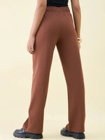 Model in Dark Rust Wide Leg Pintuck Trackpants by 98degreenorth, shown from the back on a plain background.