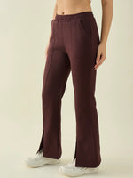 A person wearing 98degreenorth Dark Wine Women’s Fleece Flared Bootcut Sweatpants with white sneakers, waist to feet.