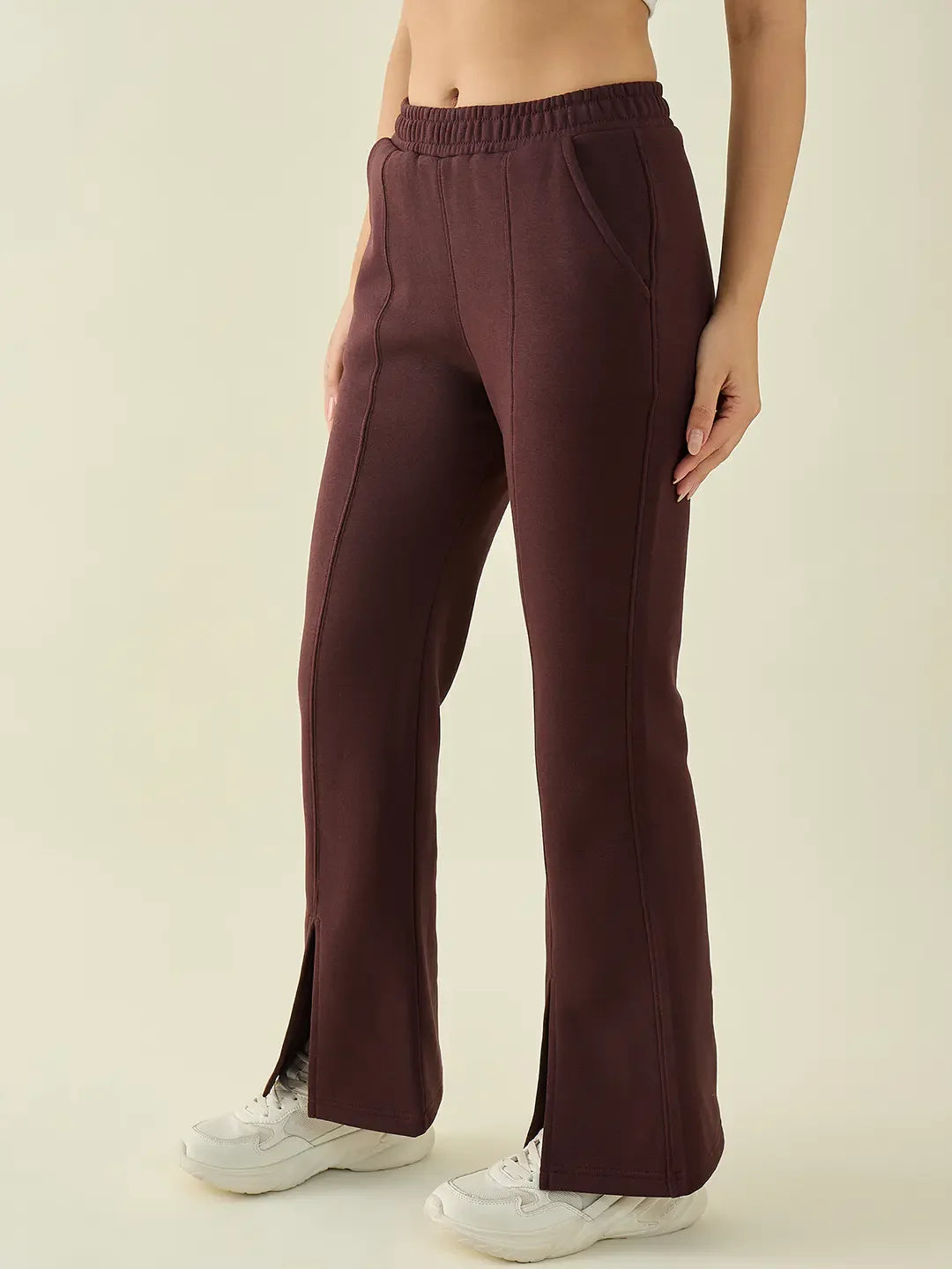 A person wearing 98degreenorth Dark Wine Women’s Fleece Flared Bootcut Sweatpants with white sneakers, waist to feet.